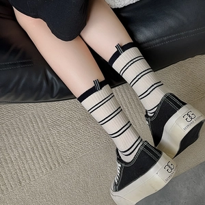 Women's striped crew socks in cream knit with black stripes and unique heel tab design