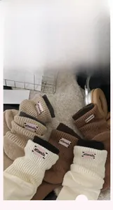 Close-up of knit crew socks with embroidered pink logo label and contrast cuff detail