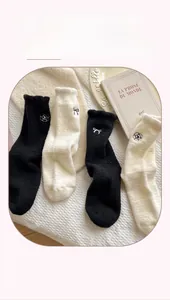 Detail of coral fleece socks with bow embroidery in black and beige tones