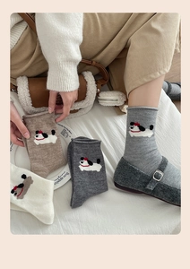 Close-up of four pairs of wool socks featuring cute dog embroidery in various neutral colors
