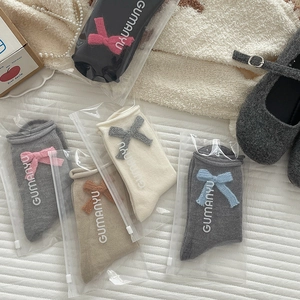 Cinque paia di calze in maglia con fiocchi decorativi in vari colori neutri e confezione
