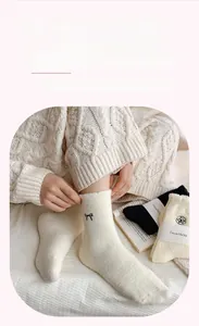 Close-up of thick plush winter socks featuring black bow and white camellia embroidery