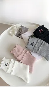 Detail of four pairs of ribbed socks in black, gray, pink, and white with bow embroidery