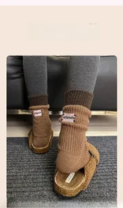 Close-up of brown knit socks with pink embroidered label and plush brown mules