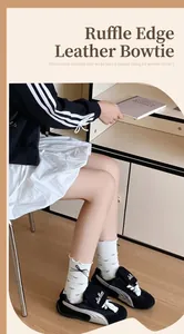 Gros plan de chaussettes en coton blanc avec nœuds en cuir noir et bords ondulés