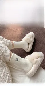 Close-up of cozy white plush slippers paired with floral embroidery winter socks
