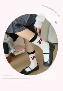 Detail of white cotton crew socks with red bow jacquard and black contrast cuffs