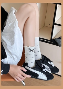 Détail de chaussettes blanches avec motifs nœuds noirs et bordure à volants