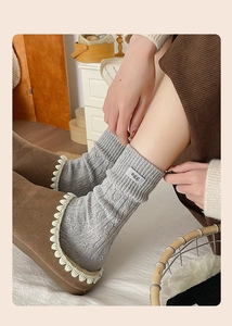 Detail of grey knitted wool socks with egg label and brown suede slippers in home setting
