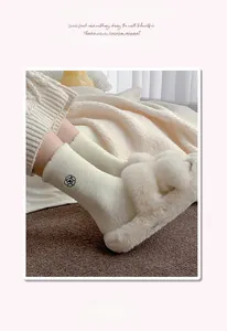 Detail of plush thermal socks with camellia embroidery and cozy white slippers on rug