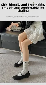 Detail of cream cotton socks with black bow embroidery and ruffled cuffs with leather shoes