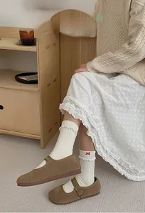 Detail of cream knit crew socks featuring scalloped edges and red bow embroidery detail