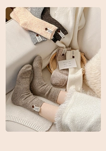 Détail de chaussettes en laine avec boutons en bois et étiquettes en tissu aux tons chauds