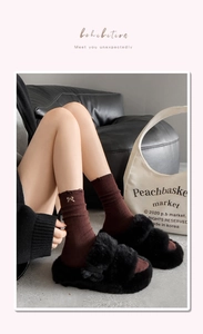 Close-up of brown ribbed socks with bow embroidery and black fuzzy platform slippers