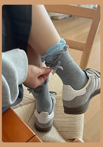 Detailed view of grey and blue socks featuring elegant ruffles and bow accents