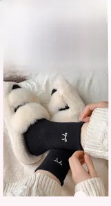 Detail of plush black thermal socks featuring a white bow embroidery with fuzzy texture