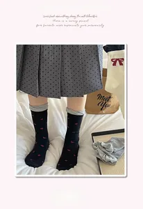 Detail of knit crew socks in black with red heart patterns and grey ribbed cuffs