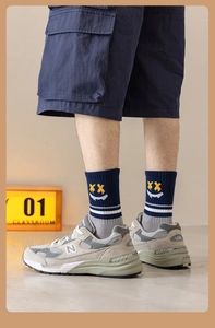 Détail de chaussettes avec broderie smiley jaune et motifs de rayures sportives