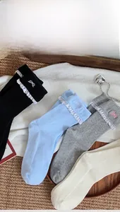 Detail of knit socks with delicate white lace trim and cute embroidered bow patterns