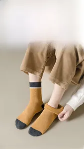 Nahaufnahme dicker ingwergelber Wollsocken mit grauer Ferse und gestreiften Bündchen