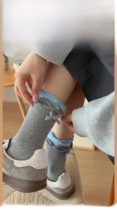Detail of dark grey crew socks featuring light blue lace ruffles and silk ribbon bow