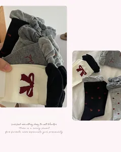 Close-up of cotton socks set with red bow accents and elasticated ruffled cuffs