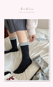 Detail of ribbed knit socks with heart patterns and bows on a cozy bedroom background