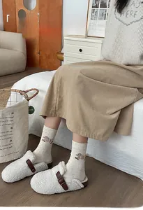 Close-up of cozy white flocked animal socks paired with plush slippers in home setting