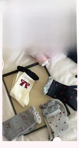 Detail of cotton crew socks with red bow embroidery and wavy lace trim in various colors