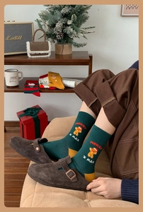 Detail of green knit Christmas socks with gingerbread man pattern in a cozy festive setting