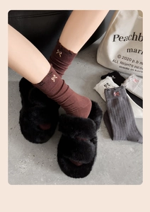 Detail view of colorful knit socks with bow embroidery and plush faux fur slippers