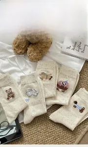 Detail of cream cotton crew socks with colorful dots and cute animal embroidery