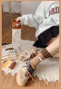 Detail of creative mid-tube socks with 3D cartoon eyes and soft earth tone stripes