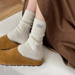 Cream knit wool socks with egg label paired with brown suede mules in earthy tones
