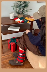 Cozy festive cotton Christmas socks in assorted holiday patterns on a warm rug