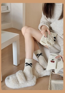 Détail de chaussettes avec nœuds noirs, cerises rouges et broderies d'ours mignons