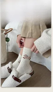 Detail of cream crew sock featuring cute sheep pattern and elastic ribbed cuff design