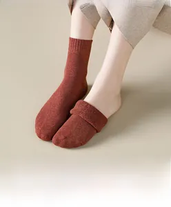 Detailed texture of thick ribbed knit crew socks in warm brick red for winter