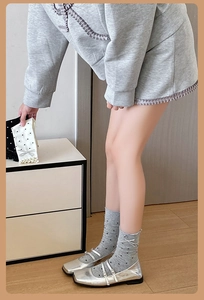 Détail de chaussettes à pois gris clair avec nœud en soie blanche et chaussures argent