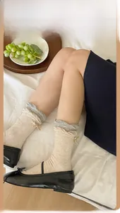 Detail of beige crew socks featuring ruffle cuffs and a small decorative bow