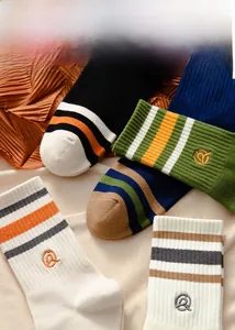 Close-up of cotton crew socks featuring three-stripe patterns and letter Q embroidery