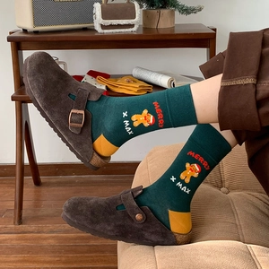 Green Christmas socks with gingerbread man pattern paired with brown suede clogs