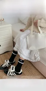 Detailed close-up of black knit mid-calf socks featuring white lace trim and bow accent