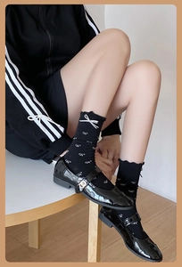 Détail de chaussettes noires avec motifs de nœuds blancs et bords à volants et chaussures