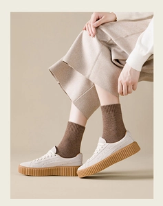 Detail of warm brown knit crew socks paired with off-white platform sneakers and trousers