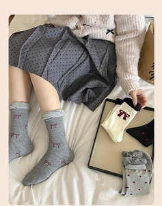 Detail of cotton crew socks with red bows, hearts and polka dots in cozy home setting