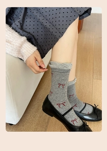 Detail of gray mid-calf socks with red bow embroidery paired with ballet flats