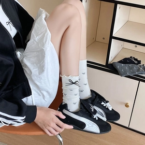 Chaussettes blanches avec motifs de nœuds noirs et bordure volantée en intérieur