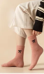 Detail of pink wool socks with knitted ribbed texture and black bow embroidery detail