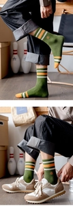 Detail of green knit crew socks with striped cuffs and yellow logo embroidery for men